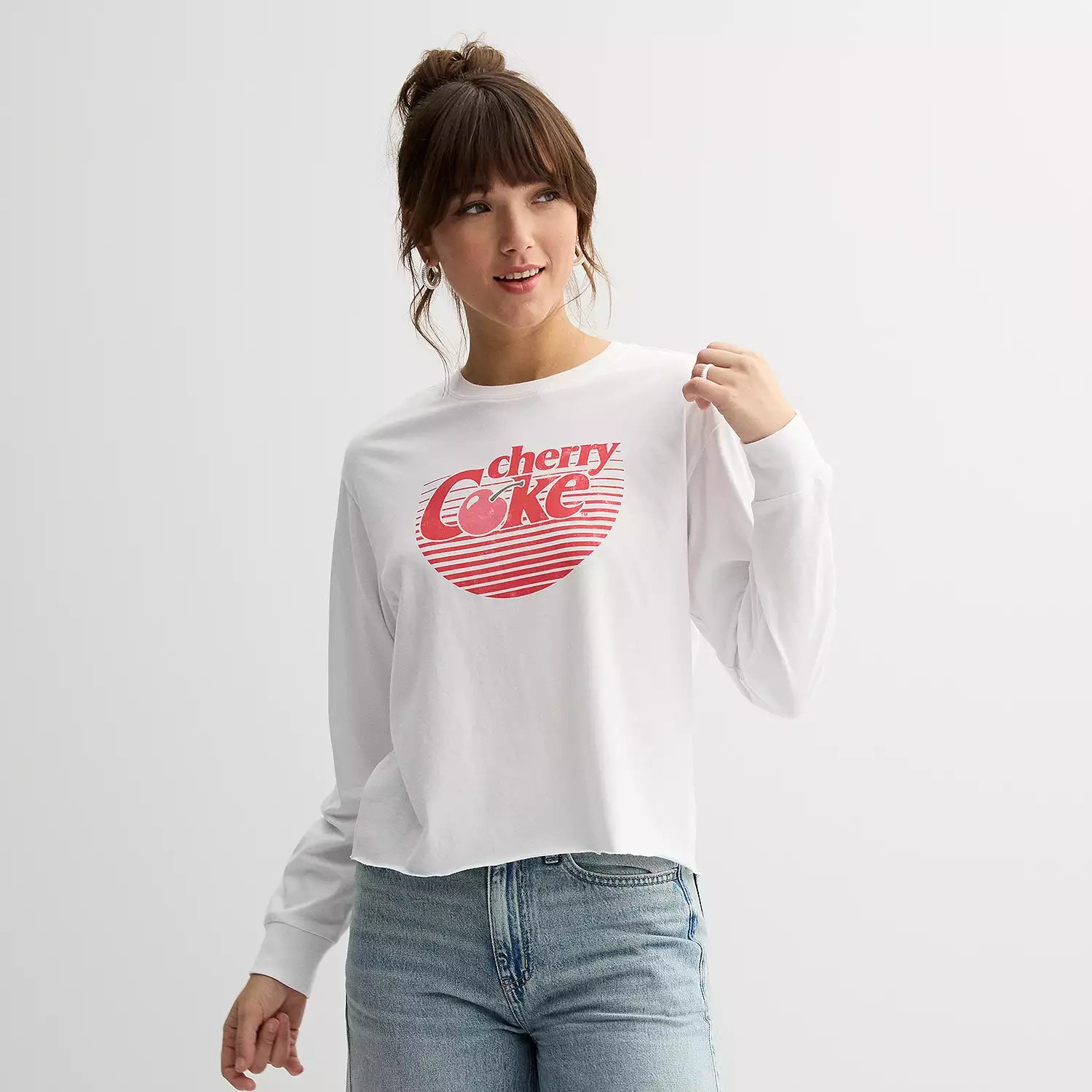 Person wearing a white sweatshirt with a red 'Coke' logo on a plain background