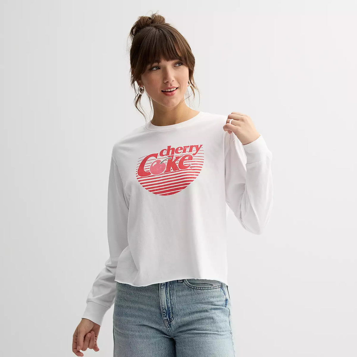 Person wearing a white sweatshirt with a red 'Coke' logo on a plain background