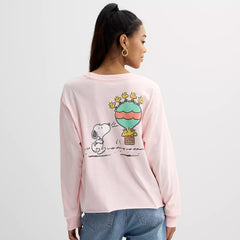 Person wearing a pink long-sleeve shirt with a cartoon design on a plain background